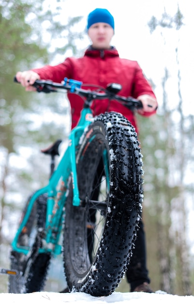 Un ragazzo tiene una fatbike in una foresta invernale