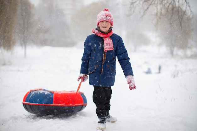 Un ragazzo tira una slitta trainata da tubi sulla neve in una giornata invernale