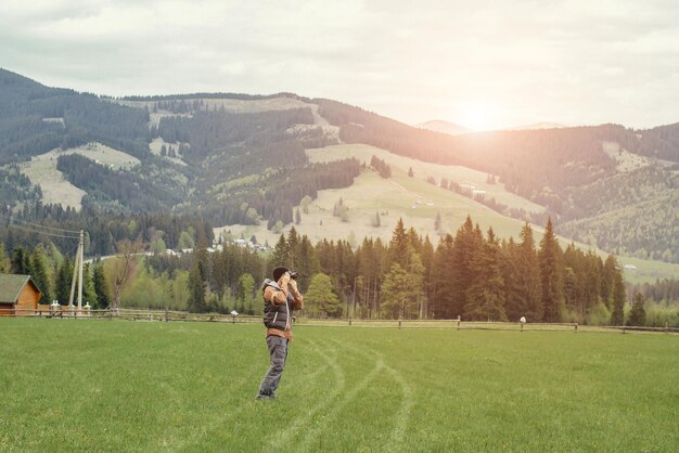 Un ragazzo viaggia con una macchina fotografica in montagna