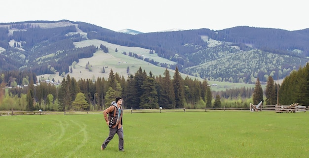 Un ragazzo viaggia con una macchina fotografica in montagna