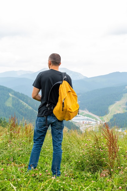 Un ragazzo viaggia con uno zaino giallo attraverso luoghi pittoreschi con splendidi paesaggi di montagna.