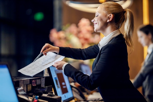 Un receptionist felice sta dando i documenti a un ospite per iscriversi