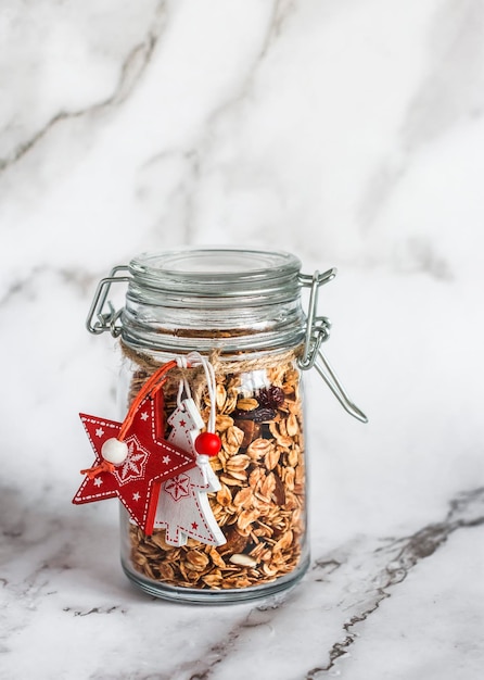 Un regalo di Natale commestibile è il granola fatta in casa con mandorle, fichi secchi e mirtilli rossi su sfondo chiaro Copia spazio