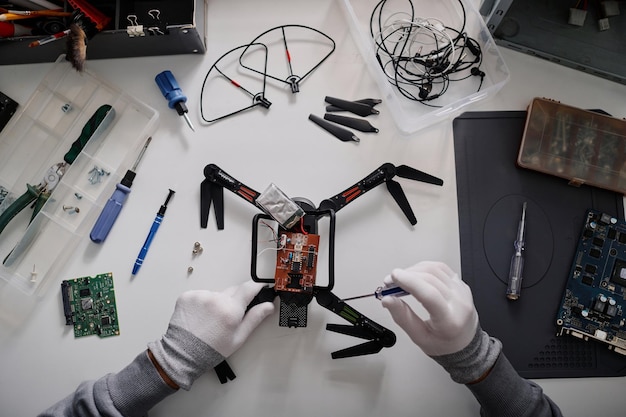 Un riparatore ripara un drone stringendone le caviglie con un cacciavite