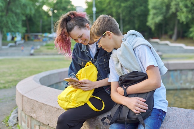 Un ritratto all'aperto di due adolescenti parlanti con lo smartphone