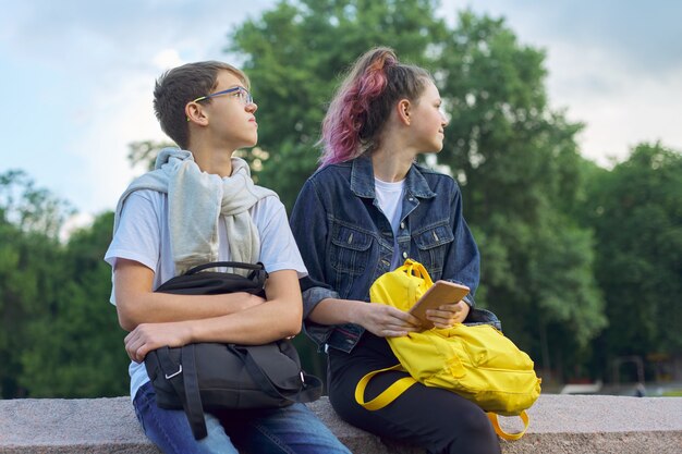 Un ritratto all'aperto di due adolescenti parlanti con lo smartphone