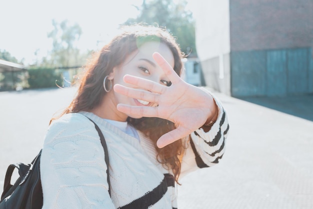 Un ritratto del primo piano di una donna africana che esamina la macchina fotografica e sorride. L'abbigliamento è un classico bianco più dolce. Studente al concetto di università, apprendimento felice, giornata di sole