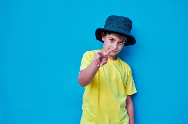 Un ritratto del ragazzo ribelle in maglietta gialla e cappello facendo