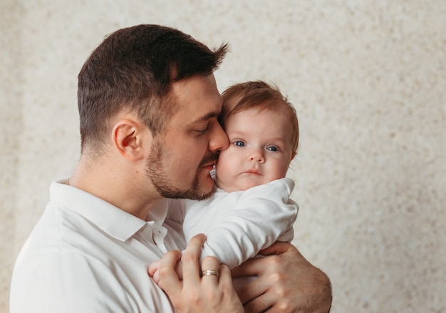 Un ritratto delicato di un giovane padre e di una bambina su una superficie luminosa. Tenerezza, genitorialità