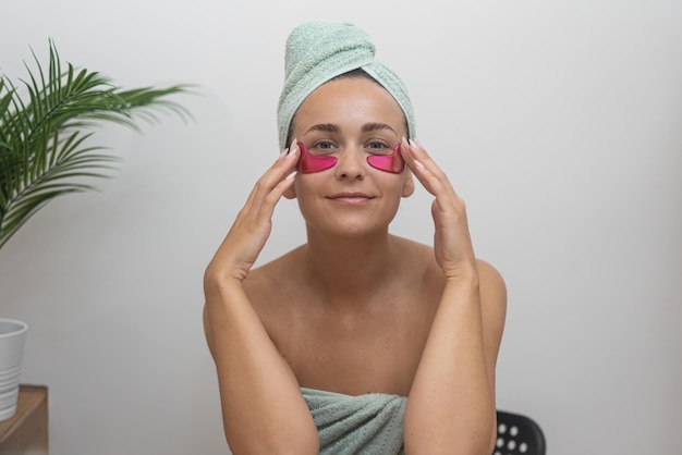 Un ritratto della routine di cura della pelle di una signora che utilizza bende per gli occhi durante una giornata in spa a casa per la bellezza del viso