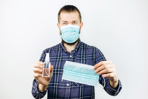 Un ritratto di Close-up di un ragazzo emotivo in una maschera medica con un disinfettante nelle sue mani. Fermare la diffusione dell'infezione da coronavirus. COVID 2019