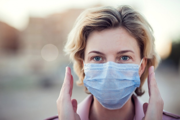 Un ritratto di donna con maschera medica all'aperto. Concetto di persone, assistenza sanitaria e medicina