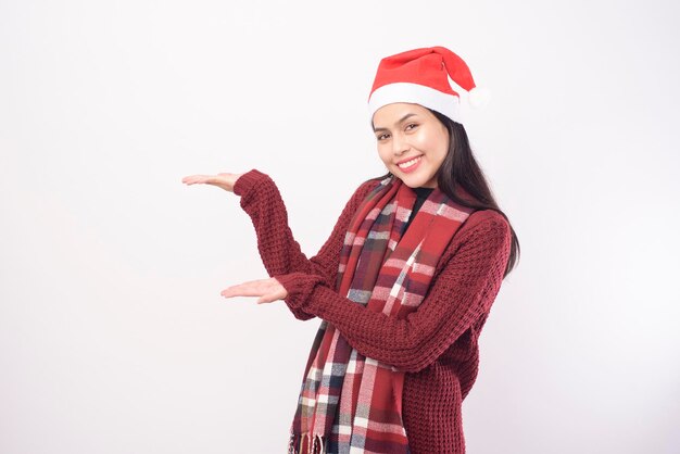 Un ritratto di giovane donna sorridente che indossa il cappello rosso di Babbo Natale isolato sfondo bianco studio.