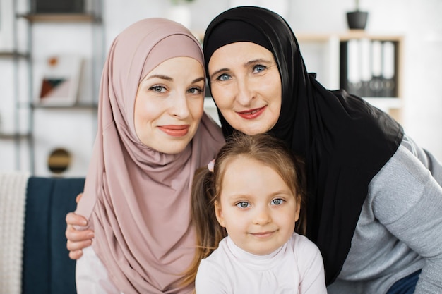 Un ritratto di tre generazioni di donne musulmane guarda la macchina fotografica in posa per una foto di famiglia