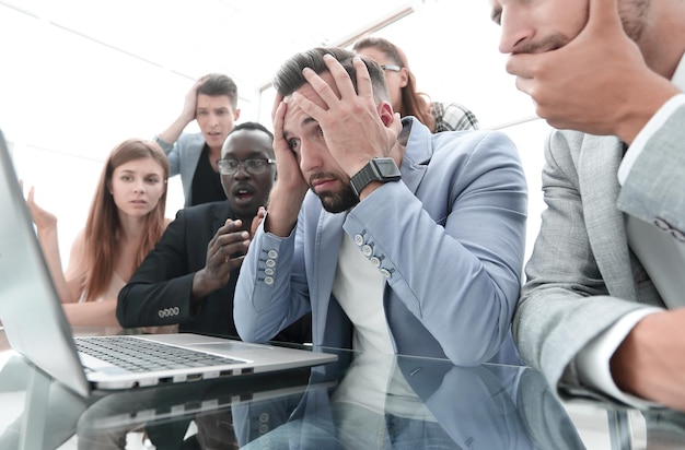 Un ritratto di tre uomini d'affari attraenti alla moda seduti insieme in piedi insieme nella stazione del posto di lavoro guardando lo schermo del laptop con un'espressione infelice sconvolta che ha problemi a non riuscire