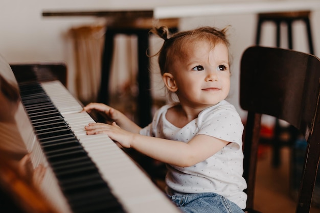 Un ritratto di un simpatico bambino felice di 2 anni che si diverte alla lezione di pianoforte