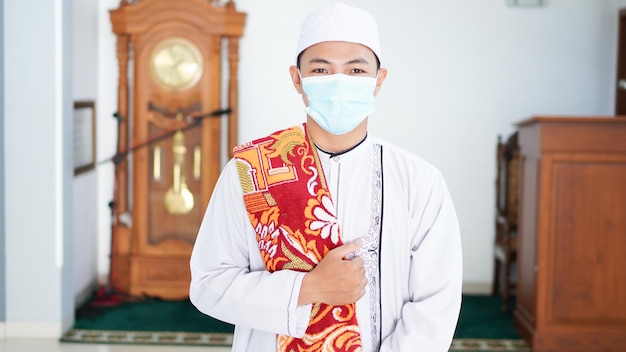 Un ritratto di un uomo musulmano asiatico elegante alla moschea, dopo lo sholat, indossando una maschera