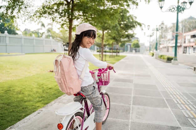 Un ritratto di una bambina allegra in bicicletta nel parco