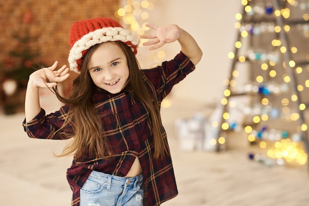 Un ritratto di una bambina in una casa di Natale decorato in un cappello di Natale