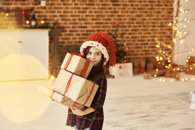 Un ritratto di una bambina in una casa di Natale decorato in un cappello di Natale