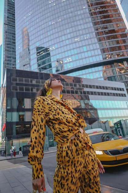 Un ritratto di una donna felice vestita alla moda che posa per un servizio fotografico per le strade