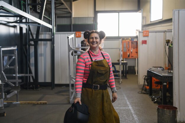 un ritratto di una donna saldatrice che tiene un casco e si prepara per una giornata lavorativa nell'industria metallurgica. Foto di alta qualità