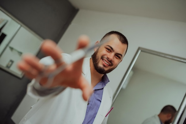 Un ritratto di una fotografia di un parrucchiere sorridente in un'uniforme da lavoro che tiene le forbici in mano Foto di alta qualità