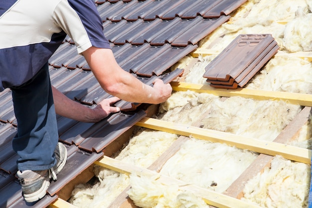 Un roofer che pone le mattonelle sul tetto