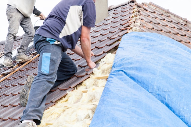 Un roofer che pone le mattonelle sul tetto