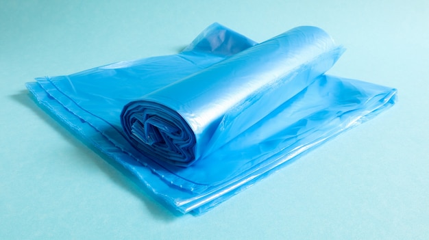 Un rotolo di sacchetti di immondizia di plastica in blu su sfondo blu. Sacchetti progettati per contenere la spazzatura e utilizzati a casa e collocati in vari contenitori per la spazzatura.