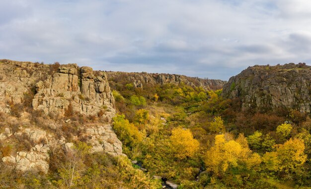 Un ruscello scorre nel Canyon Aktovsky, Ucraina. Alberi autunnali e grandi massi di pietra intorno