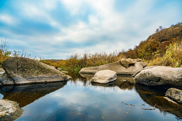 Un ruscello veloce, poco profondo e pulito scorre tra grandi pietre lisce bagnate circondate da alti grumi secchi che ondeggiano al vento nella pittoresca Ucraina