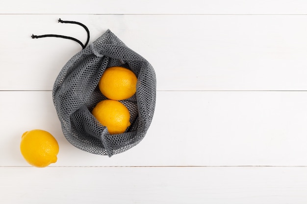 Un sacchetto della spesa riutilizzabile con limoni su sfondo bianco