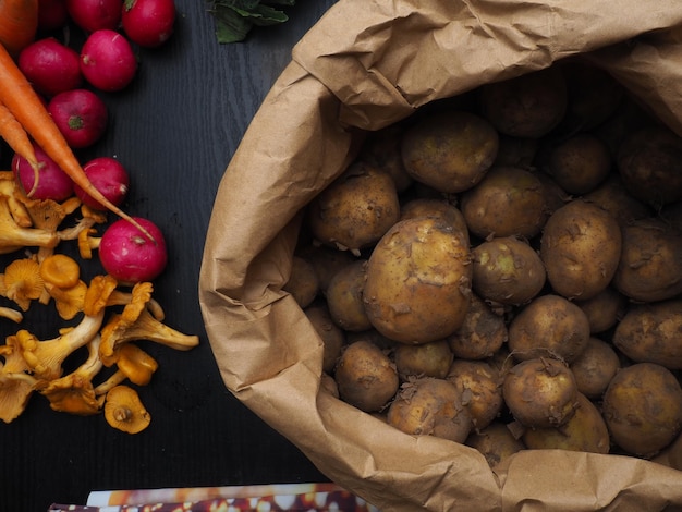 Un sacchetto di patate è su un tavolo accanto a una scatola di funghi.