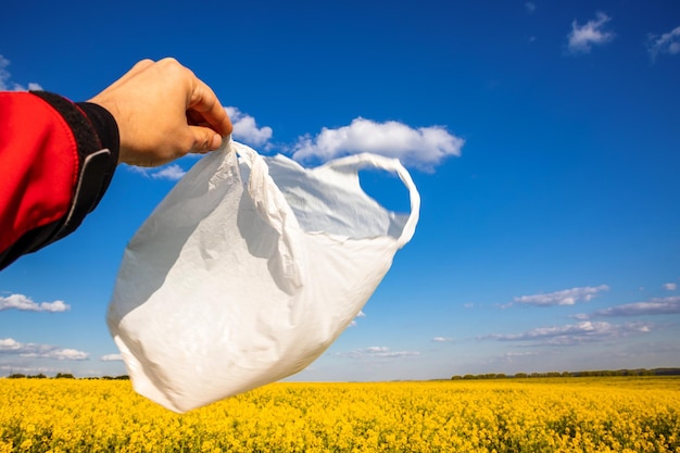 Un sacchetto di plastica nelle mani sullo sfondo di un campo di colza