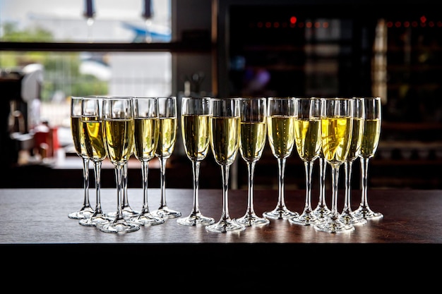 Un sacco di bicchieri da vino con un delizioso champagne fresco o vino bianco al bar o al catering per eventi. Sfondo di alcol.