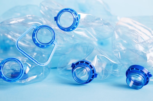 Un sacco di bottiglie usate sgualcite vuote di plastica su uno sfondo blu concetto di rifiuti e inquinamento