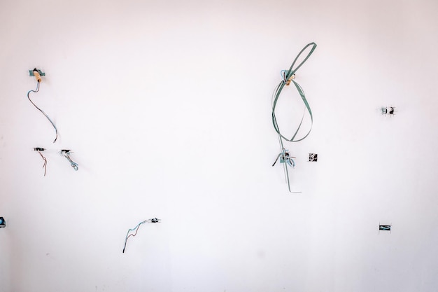 Un sacco di fili scoperti su un muro bianco, primi piani