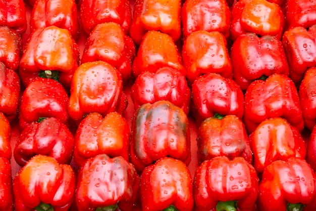 Un sacco di grandi peperoni dolci rossi piegati in file