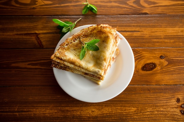 Un sacco di pancake pancake sottili in un piatto su un tavolo di legno