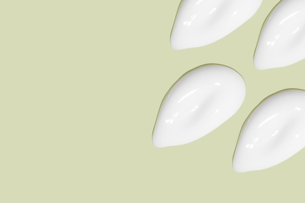 Un sacco di sbavature di crema cosmetica Superficie liscia e leggera In fila Ad angolo Vista dall'alto Texture di crema che scorre Tratti cremosi liquidi Su sfondo verde Banner di sfondo cosmetico