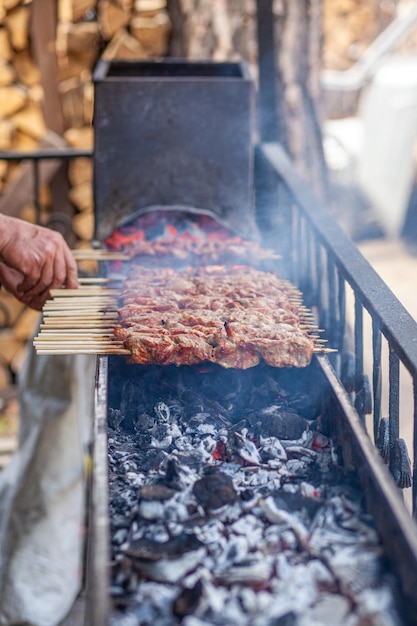 Un sacco di spiedini di carne succosi in fila sulla griglia. Pezzi di carne infilati su spiedini di legno alla griglia.