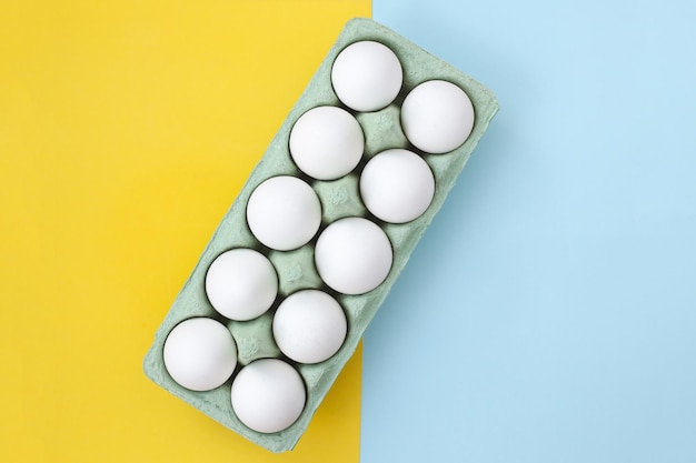 Un sacco di uova di gallina bianche su uno sfondo colorato uniforme e luminoso
