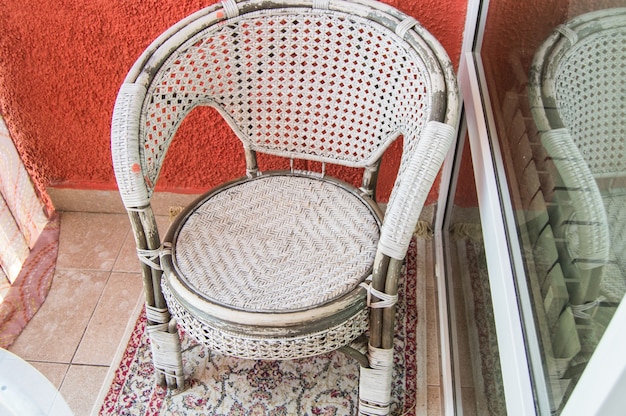 Un salottino sul balcone con una sedia di vimini in rattan, un tappeto. Vista dall'alto