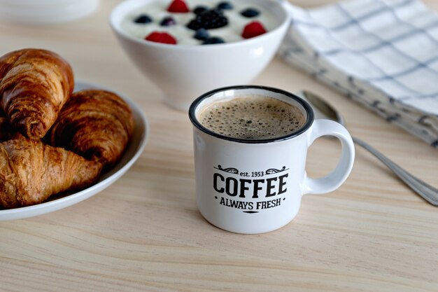 Un sano concetto breaskfast con caffè yogurt frutti rossi e croissant sulla tavola di legno