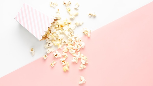 Un secchio a righe di popcorn sullo sfondo bianco e rosa vista superiore e spazio di copia