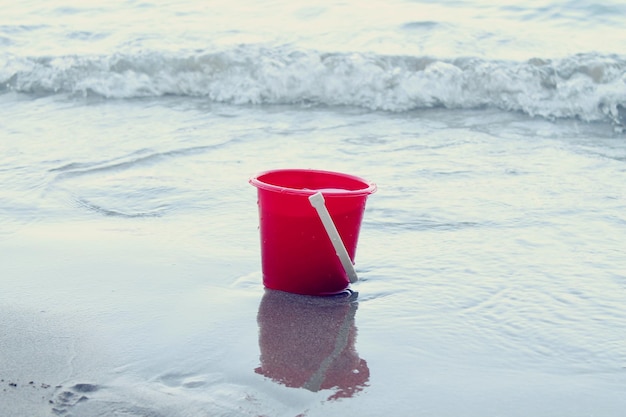 Un secchio rosso sulla riva del mare