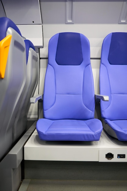 Un sedile blu in un aereo con un caricabatterie bianco al centro.