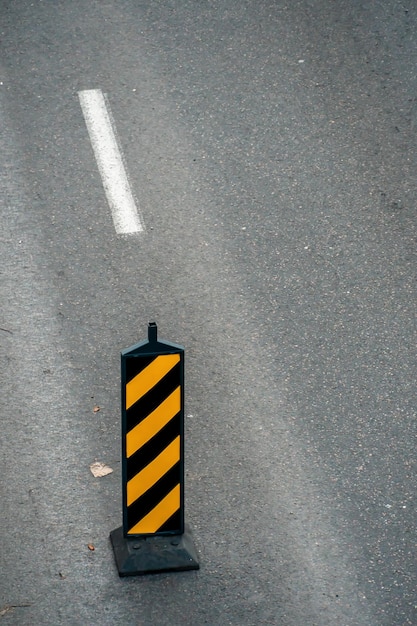 Un segnale stradale che indica la separazione dei flussi di traffico davanti a un tratto pericoloso di strada durante i lavori di riparazione Delineatore del separatore stradale