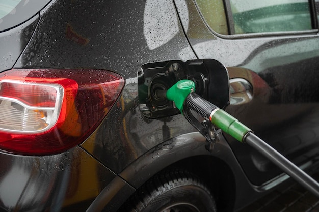 Un serbatoio aperto con un tubo del carburante alla stazione di servizio